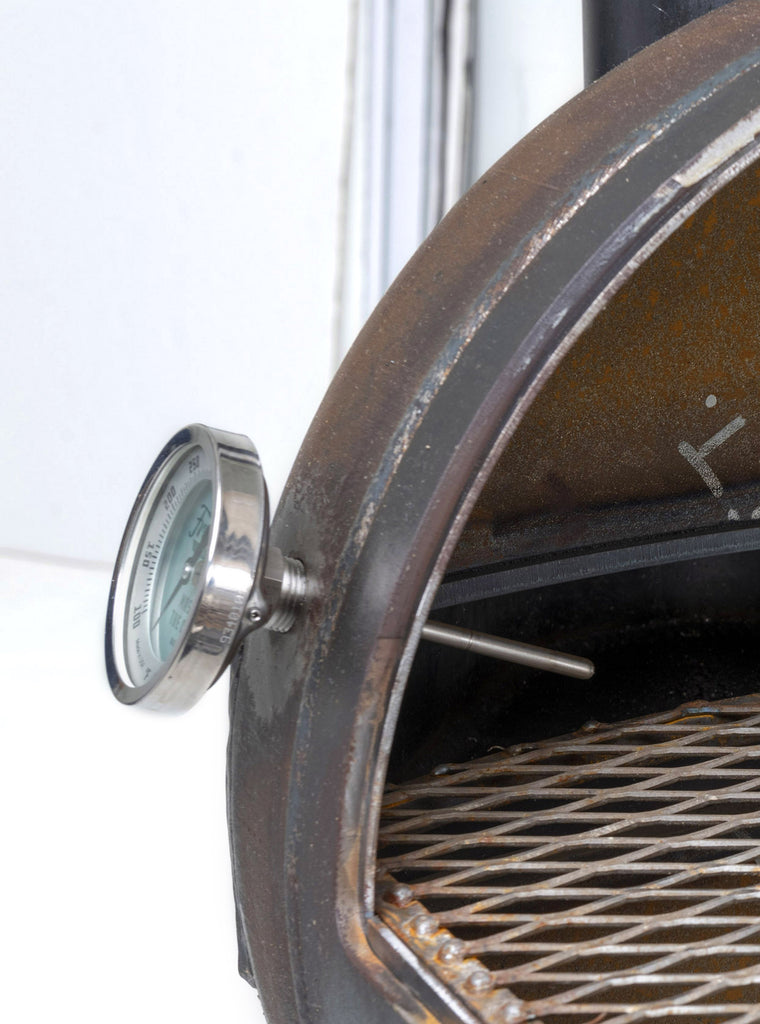 Thermometer affixed to side of barbecue pit